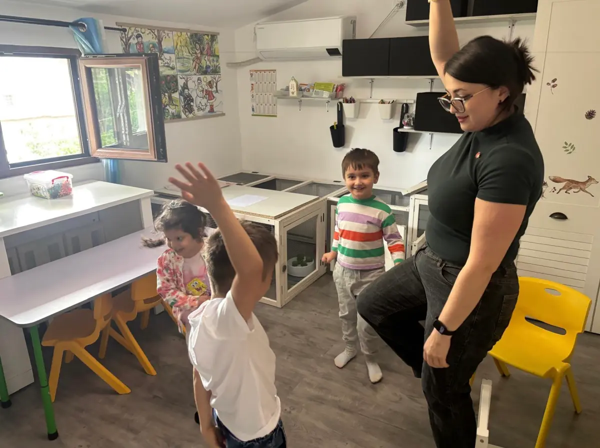 Copii și o voluntară dansând împreună într-o cameră de terapie